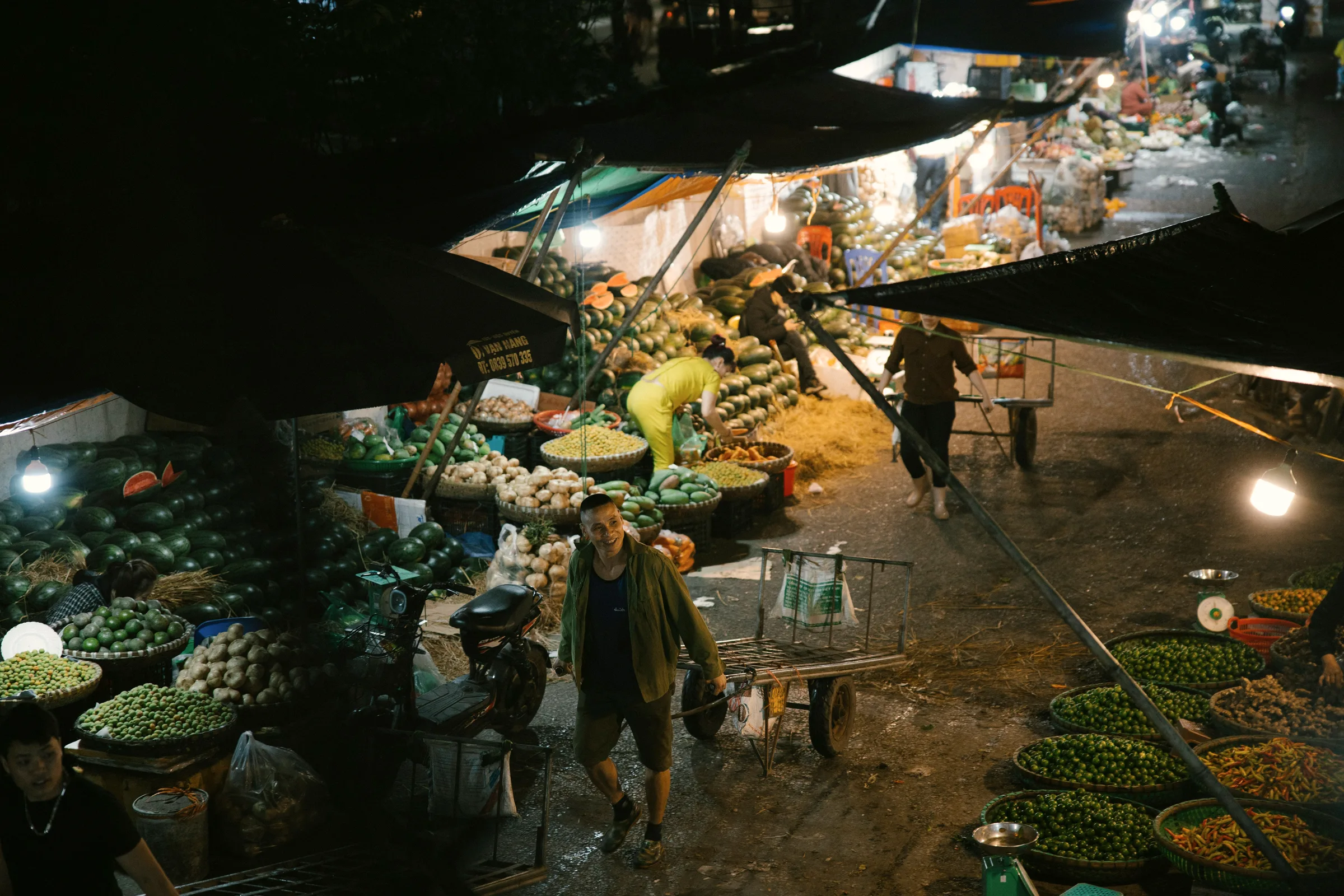 Vendors and produce crates under awnings at a covered market