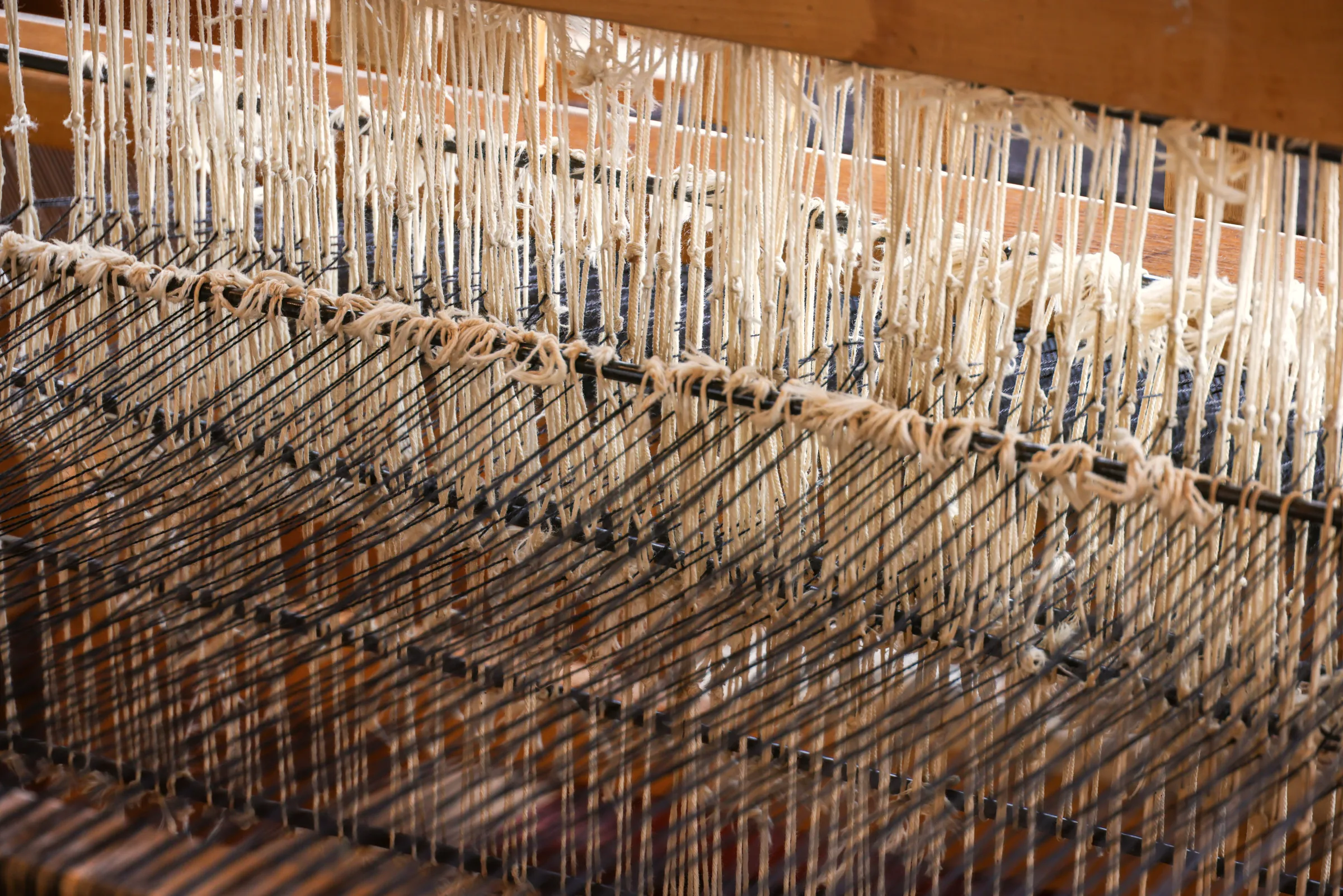 Raw silk threads stretched across a wooden loom