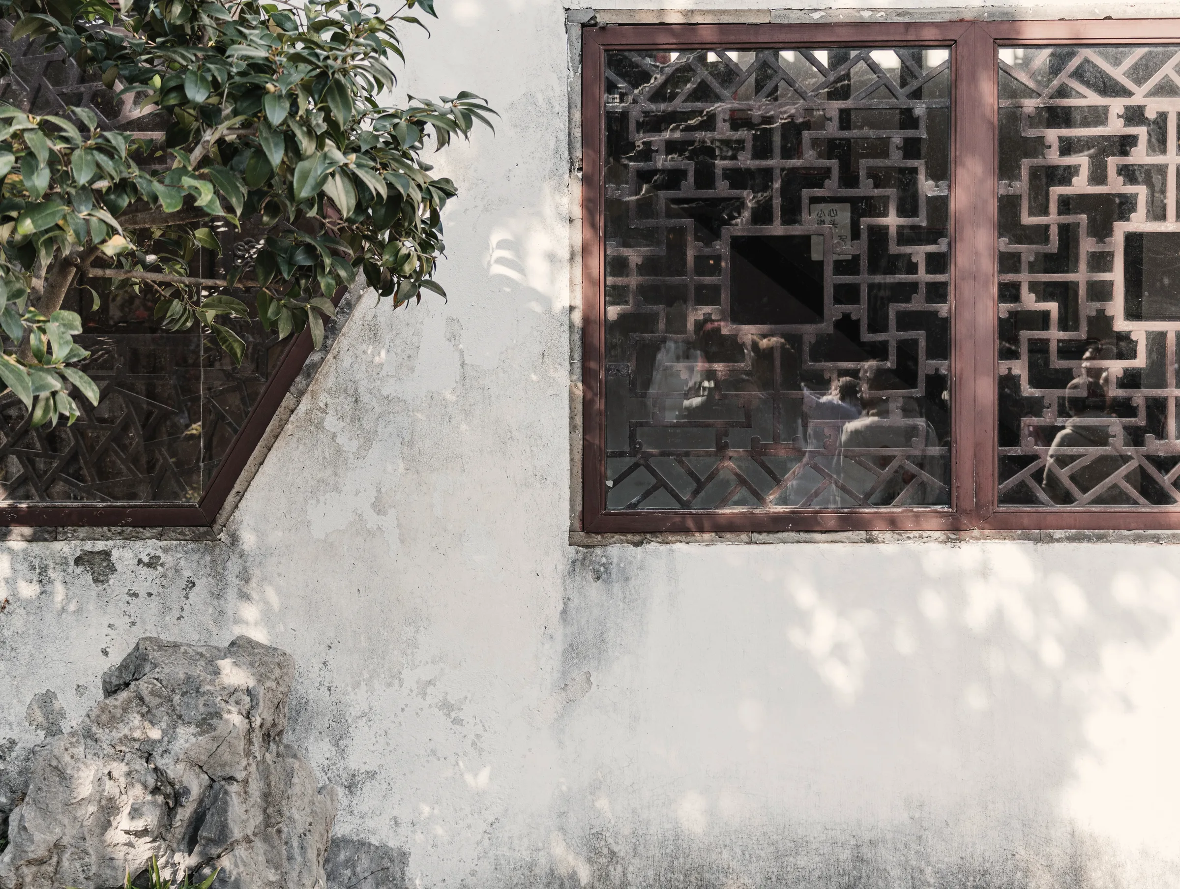 Carved lattice window set into a weathered white wall