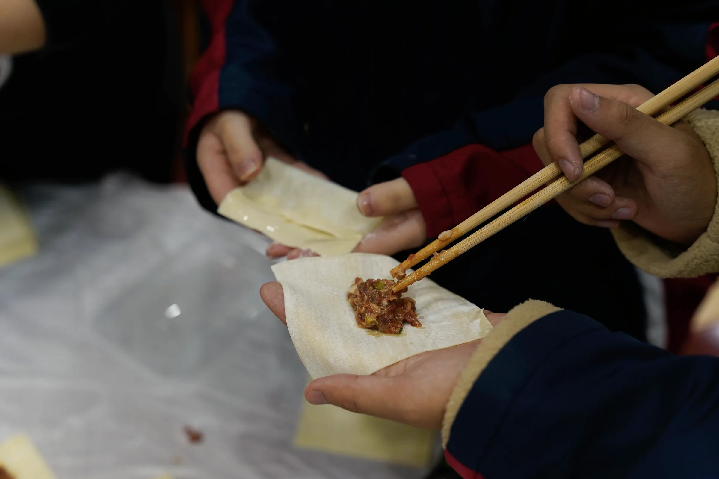 Long strands of hand-pulled dough held above a floured board