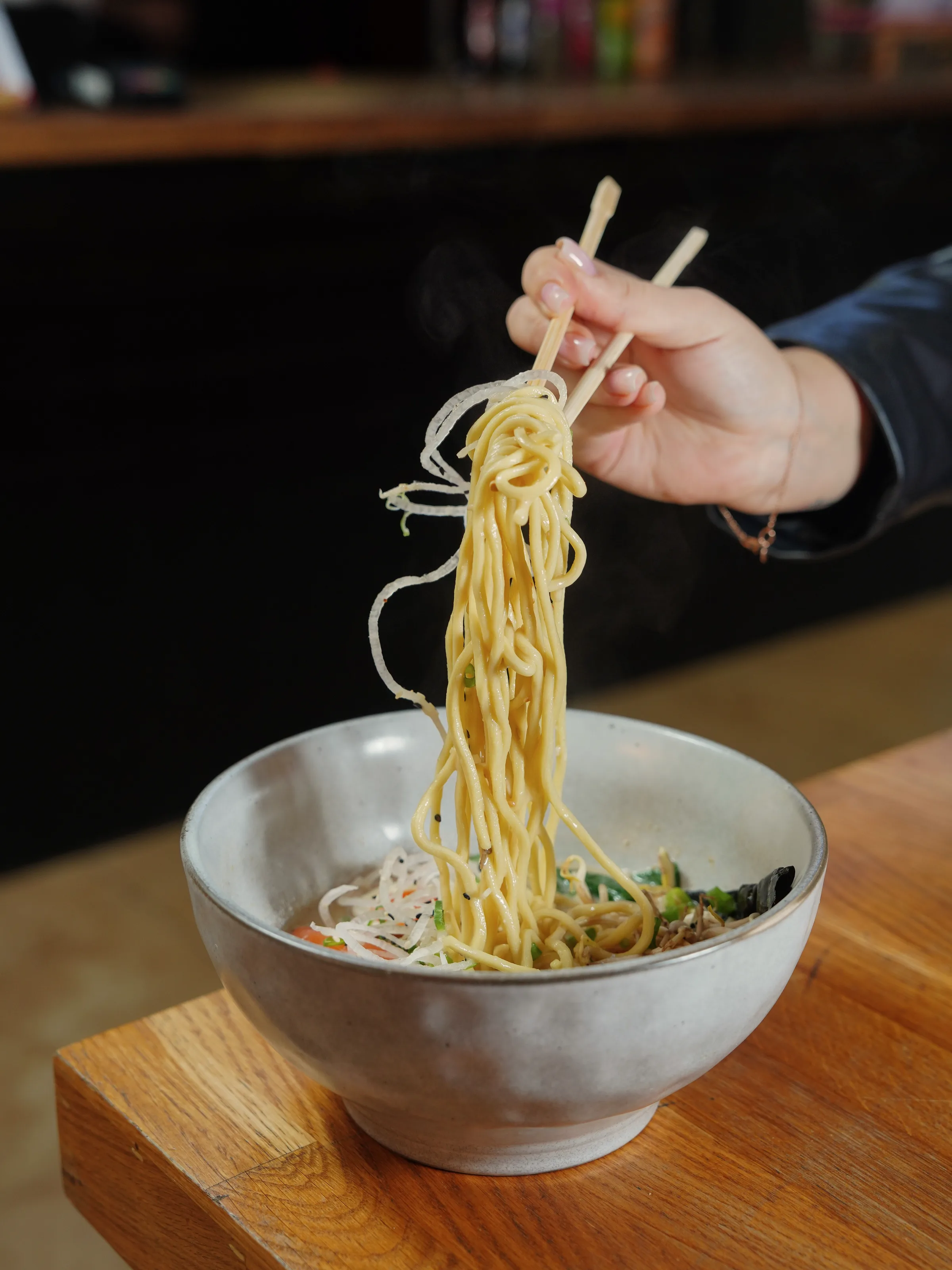 Dough being stretched between two hands over a counter